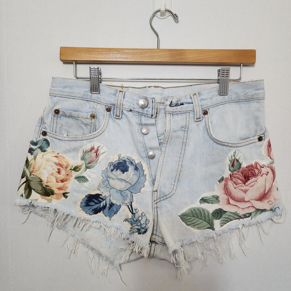 Denim shorts, adorned with floral raw-edge appliqués crafted by hand.